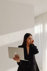 Kaboompics - Woman Holding a Laptop and Smartphone in a Sunlit Room