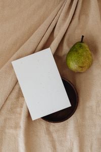 Kaboompics - Top-Down Pear and Blank Card on a Dark Wooden Plate