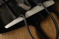 Kaboompics - Laptop Edge Over Black Leather Bag on Wooden Desk