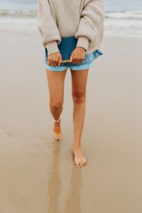 Kaboompics - Close-Up Beach Lifestyle Portrait of a Woman Carrying a Book in a Knit Sweater and Denim Shorts