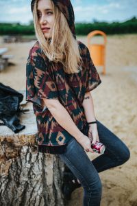 Kaboompics - Woman Holding a Cola Can While Seated on a Beach Stump
