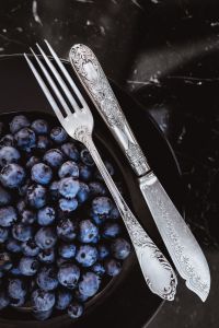 Fresh blueberries on a black plate with vintage cutlery