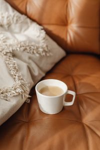 Kaboompics - Vertical Coffee Mug and Textured Throw on Caramel Leather Sofa for Cozy Interior Stories