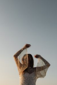 Kaboompics - Faceless Woman Raising Arms in Sequin Dress at Sunset