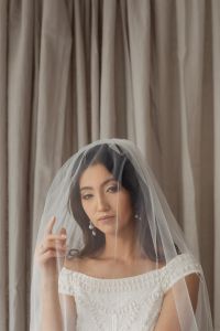 Kaboompics - Bride With a Wedding Veil Over Her Face Against Taupe Curtains
