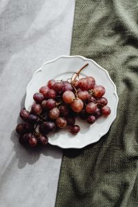 Kaboompics - Red Grapes on a White Plate with Copy Space and Linen Texture