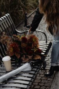 Kaboompics - Woman Arranging an Autumn Bouquet on a Black Metal Bench