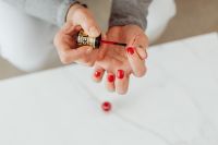 Kaboompics - Red Nail Polish Brush and Manicured Hand in a Bright Marble Beauty Scene