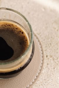 Kaboompics - Close Up Espresso Crema in a Glass Cup with Beige Copy Space