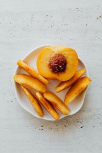 Kaboompics - Close-Up Peach Half and Slices on Light Stone Table