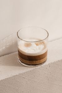 Kaboompics - Glass Latte Centered on Textured Stone, Minimal Beige Background