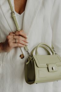 Kaboompics - Woman Holding Sage Green Leather Handbag by Its Strap, White Blazer Detail