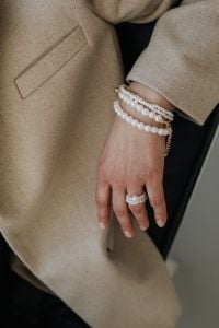 Kaboompics - Close-Up of Pearl Bracelet and Ring Against Beige Blazer Sleeve