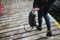 Kaboompics - Woman with a black bag and a can of coke walking on a wooden pier