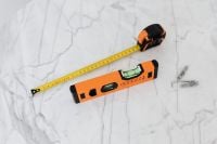 Kaboompics - Overhead Home Repair Tool Layout with Spirit Level, Tape Measure and Wall Anchors on Marble