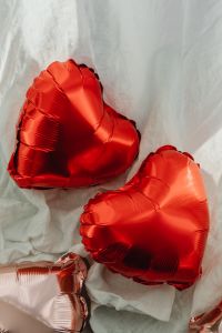 Kaboompics - Two Red Foil Heart Balloons in Close Up on White Sheer