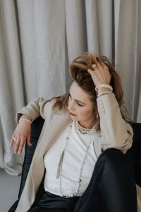 Kaboompics - Woman Adjusting Her Hair with Pearl Bracelets and Drop Earrings