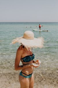Kaboompics - Woman in Raffia Sun Hat Collecting Shells in Shallow Water