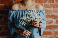 Kaboompics - A woman in a blue dress holds a branch of Baby's Breath flower