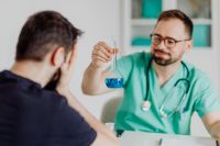 Kaboompics - Doctor Showing Blue Test Flask to Patient
