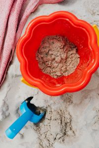 Kaboompics - Close-Up of Sand in a Red Beach Bucket with Blue Shovel for Summer Play