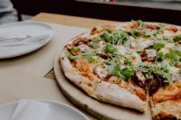 Kaboompics - Round Pizza Beside a White Plate at a Cozy Restaurant