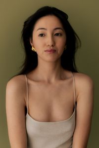 Kaboompics - Asian Woman Wearing Gold Statement Earrings in Beige Tank Top, Olive Green Background