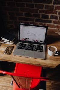 Kaboompics - Creatives desk with laptop, camera, journals and books in front of brick wall
