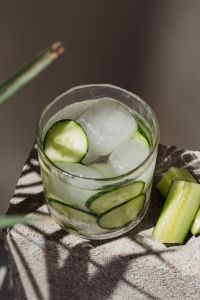 Kaboompics - Moody Cucumber and Lime Detox Water with Ice and Fresh Cucumber Sticks on Dark Stone, Summer Drink Still Life