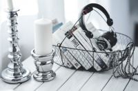 Kaboompics - Book Basket with Over-Ear Headphones and White Candlesticks