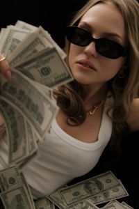Kaboompics - Woman in Sunglasses Holding a Fan of Dollar Bills
