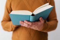 Kaboompics - A man in a brown sweater reading a book, white background