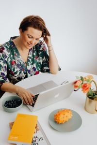 Kaboompics - Woman Working on a Laptop with Fruit and Flowers at Home