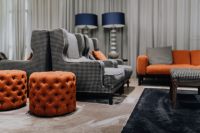 Kaboompics - Luxury Living Room with Tufted Poufs, Patterned Armchairs and Orange Sofa