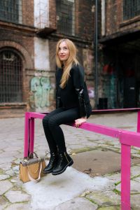 Kaboompics - Urban Streetwear Portrait Sitting on a Fuchsia Rail with Beige Handbag and Chunky Boots