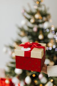 Kaboompics - Red Gift Box Held in Front of a Blurred Christmas Tree