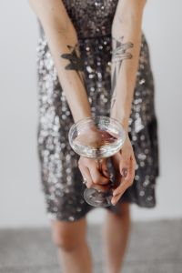Kaboompics - Portrait Crop of Tattooed Hands Holding Champagne in Sequin Dress