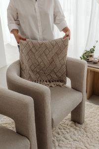 Kaboompics - Woman Arranging a Textured Throw Blanket on a Beige Armchair