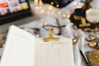 Kaboompics - Clipped Year Planner With Laptop And Jewelry On Bed