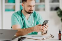 Kaboompics - Medical Professional Typing on Smartphone at Desk