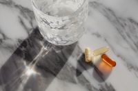 Kaboompics - Amber and Herbal Capsules Beside a Water Glass
