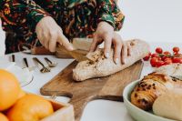 Kaboompics - Woman is cutting bread on cutting board