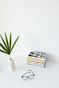 Kaboompics - Portrait Book Stack and Eyeglasses Framed by Palm Leaves