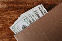 Kaboompics - US Dollar Banknotes Peeking from a Brown Wallet on Wood, Cash Savings Concept