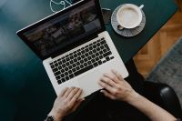 Kaboompics - Hands Typing on Laptop beside Coffee and Earbuds in a Dark Home Office