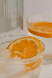 Kaboompics - Close-Up of Orange Slice in a Textured Glass with Water, Clear Bottle and Fresh Citrus Drink