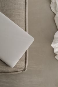 Kaboompics - Close-Up of a Silver Laptop on a Textured Greige Sofa, Minimal Home Office Background