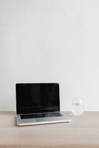 Kaboompics - Laptop and Glass of Water on Wooden Desk with Copy Space