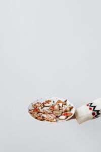 Kaboompics - Vertical Plate of Decorated Gingerbread Cookies Held by Hand, Festive Christmas Treats