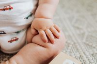 Kaboompics - Newborn Baby Hand Resting on Leg in Printed Onesie